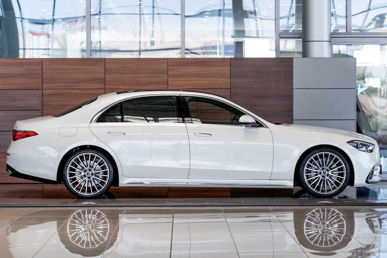 Sleek white luxury sedan showcased in a modern indoor showroom setting.