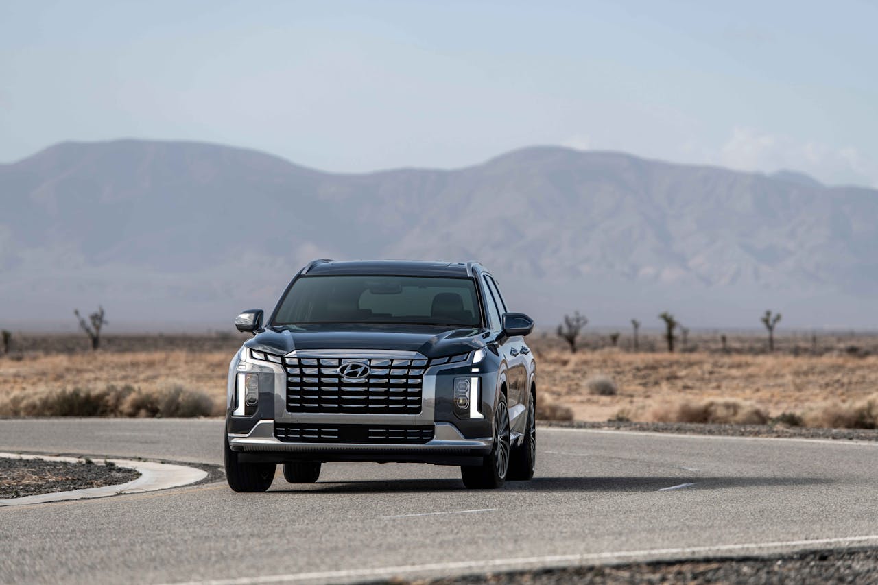 Sleek SUV traveling on an empty road through a desert landscape with mountains.