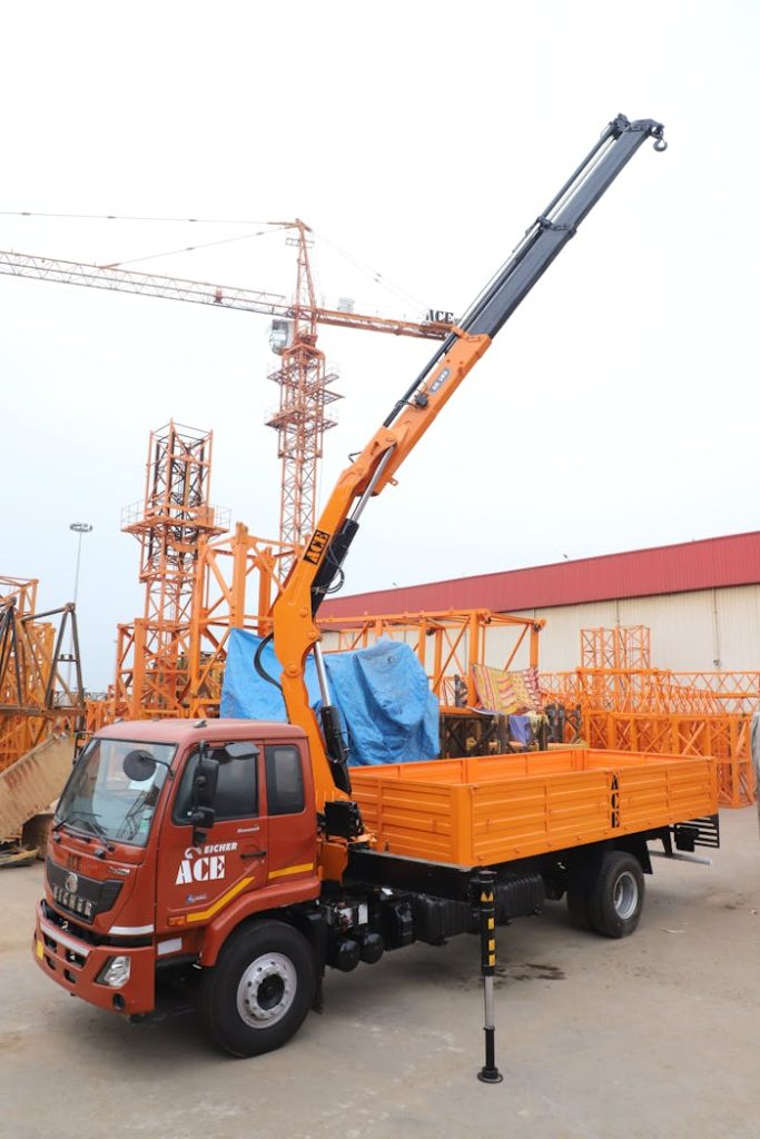 Orange ACE truck fitted with a hydraulically operated articulated boom crane in Faridabad.