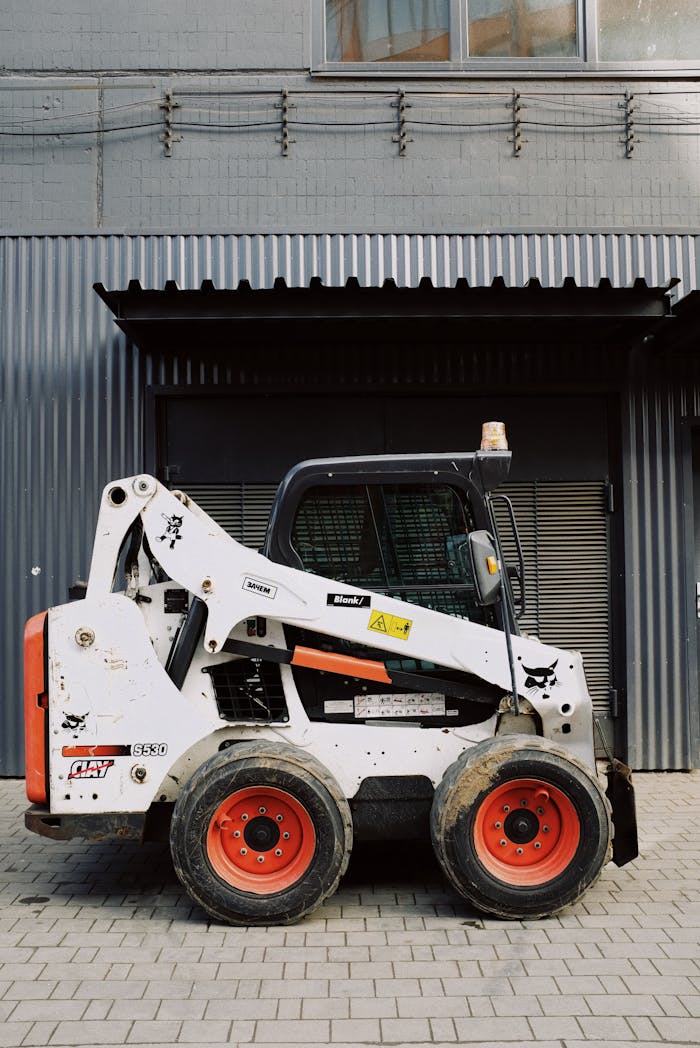 A modern skid steer loader parked outside a building for industrial work.