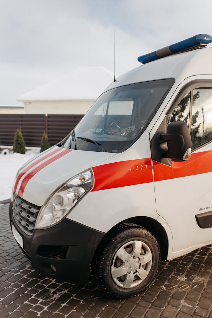 Close-up of a red and white ambulance vehicle parked outdoors during the day.